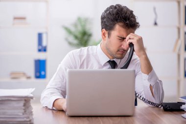 Young employee and too much work at workplace