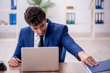 Young employee and too much work at workplace