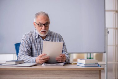 Old teacher sitting in the classroom