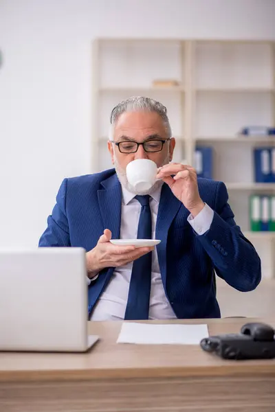 Old employee drinking coffee during break