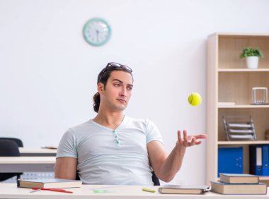 Sınav hazırlıkları sırasında tenis topu atan erkek öğrenci.