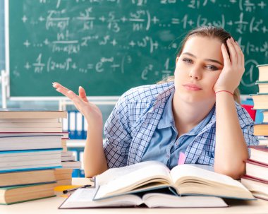 Sınıfta oturan bir sürü kitabı olan kız öğrenci.