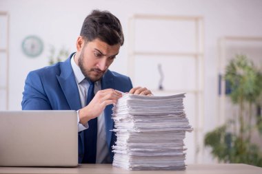 Genç bir çalışan ve ofiste çok fazla iş var.