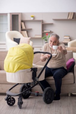 Evde yeni doğan bebeğe bakan yaşlı bir adam.