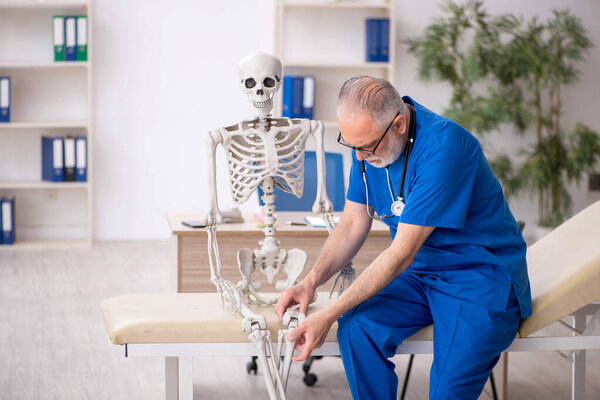 Старый врач осматривает скелет в больнице
