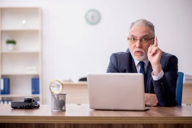 Old employee sitting at workplace