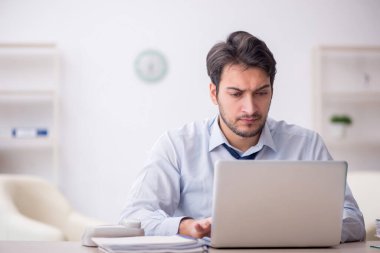 Genç işadamı işyerinde oturuyor.