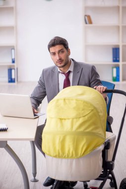 Young employee looking after newborn in the office