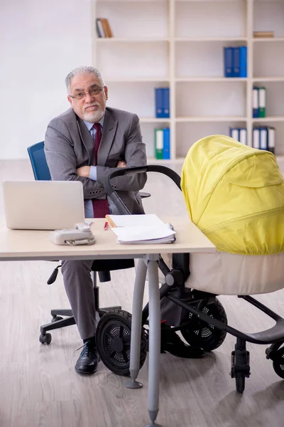 Old businessman employee looking after new born in the office