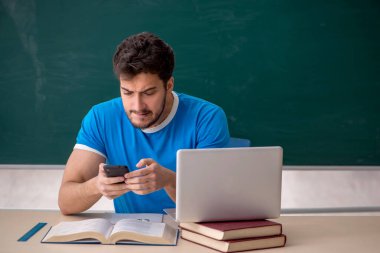 Sınıfta akıllı telefon tutan genç bir öğrenci.