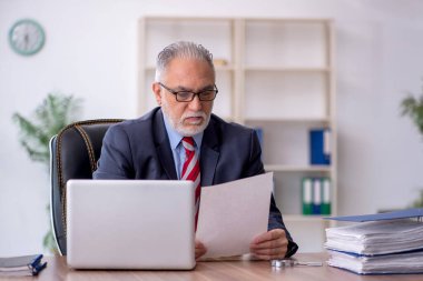 Old employee sitting at workplace