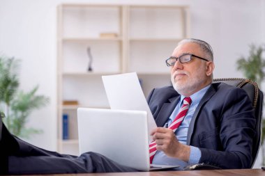 Old employee sitting at workplace