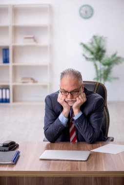 Old employee sitting at workplace