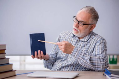 Eski öğretmen sınıfta kitap öneriyor.