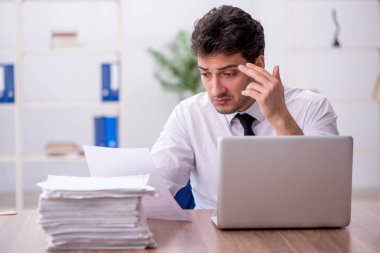 Young employee and too much work at workplace