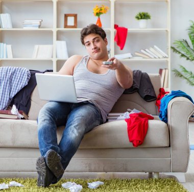 Dağınık odada çalışan genç adam.