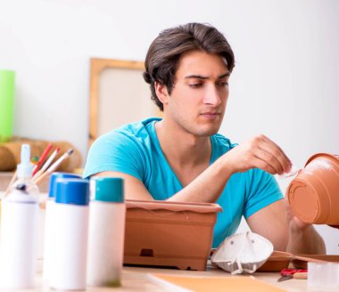 Sınıfta çömlek dekore eden genç adam.