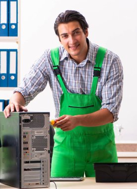 Genç mühendis ofisteki bozuk bilgisayarı tamir ediyor.