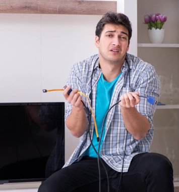 Bozuk televizyonu tamir etmeye çalışan adam.