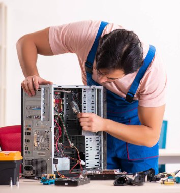 Genç erkek müteahhit bilgisayarı tamir ediyor.