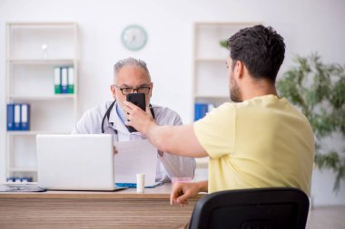 Genç hasta yaşlı doktoru ziyaret ediyor.