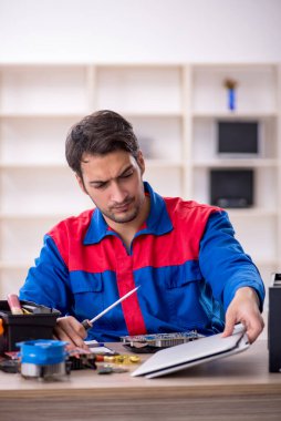 Atölyede bilgisayar tamir eden genç bir tamirci.