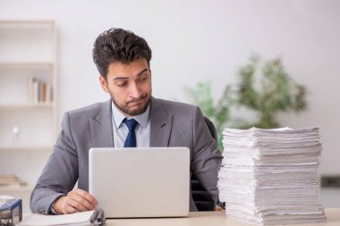 Young employee and too much work at workplace