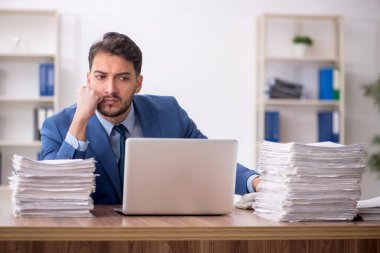 Young employee and too much work at workplace