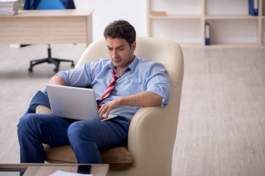 Genç işadamı işyerinde oturuyor.