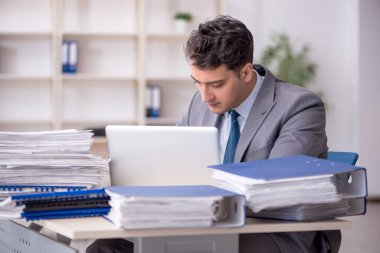 Young employee and too much work at workplace