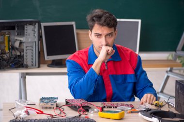 Sınıfta bilgisayar tamir eden genç bir tamirci.