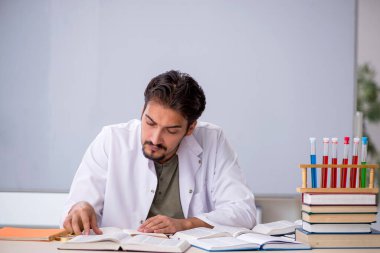 Genç kimyacı öğretmen beyaz tahtanın önünde.