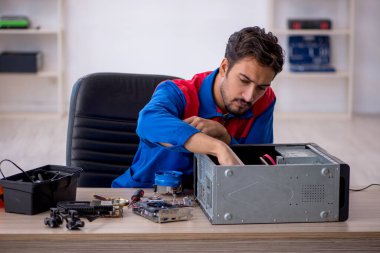 Atölyede bilgisayar tamir eden genç bir tamirci.