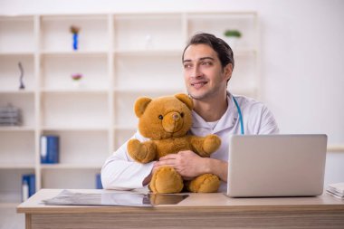 Genç doktor oyuncak ayı tutuyor.