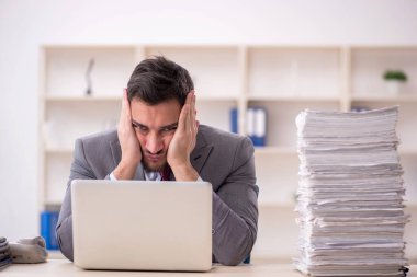 Young employee and too much work at workplace