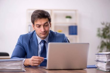 Genç bir erkek işçi ve işyerinde çok fazla iş var.