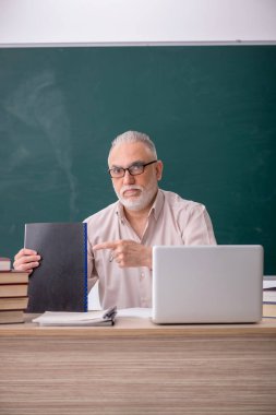 Old teacher sitting in the classroom
