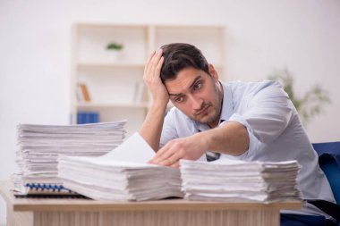Young employee and too much work at workplace