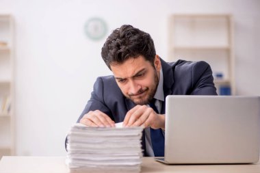 Genç bir çalışan ve ofiste çok fazla iş var.