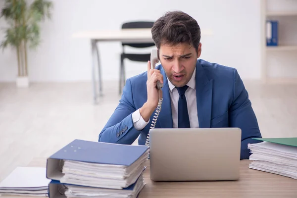 stock image Young businessman employee and too much work at workplace