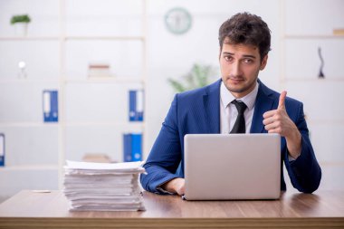 Young employee and too much work at workplace