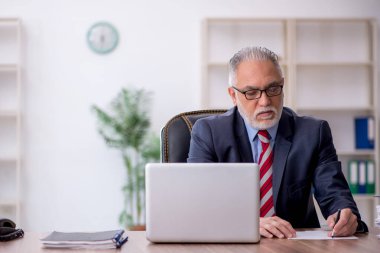 Old employee sitting at workplace