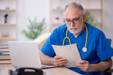 Klinikte çalışan yaşlı bir doktor.