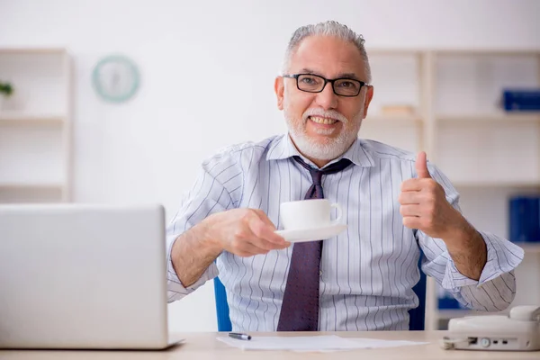 Old employee drinking coffee during break