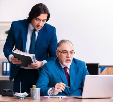 Genç ve yaşlı çalışanlar ofiste birlikte çalışıyorlar.