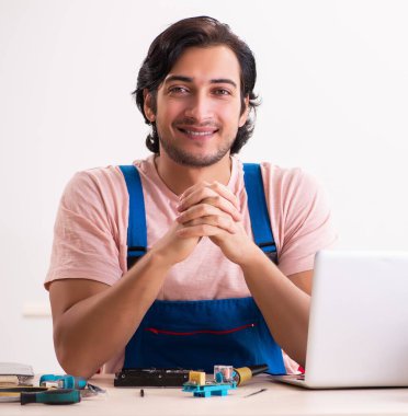 Genç erkek müteahhit bilgisayarı tamir ediyor.