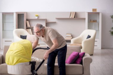 Evde yeni doğan bebeğe bakan yaşlı bir adam.