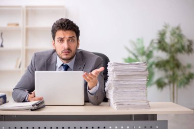Young employee and too much work at workplace