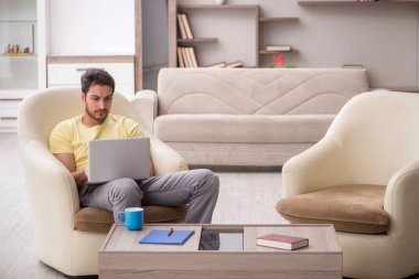 Genç erkek öğrenci salgın sırasında evden çalışıyor.