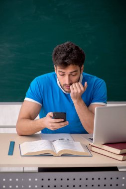 Sınıfta akıllı telefon tutan genç bir öğrenci.